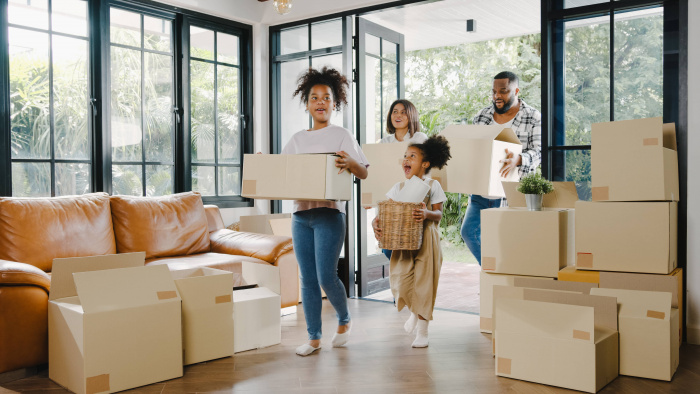 Family entering new home while carrying moving boxes