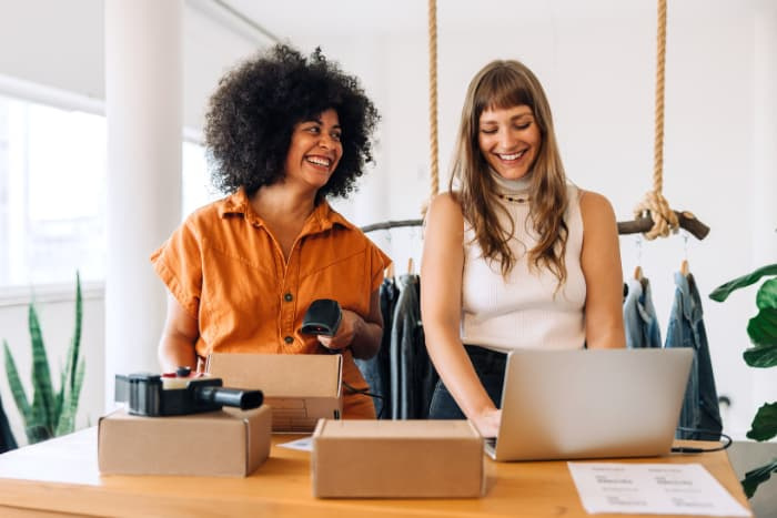 Cheerful clothing store owners preparing online orders for shipping