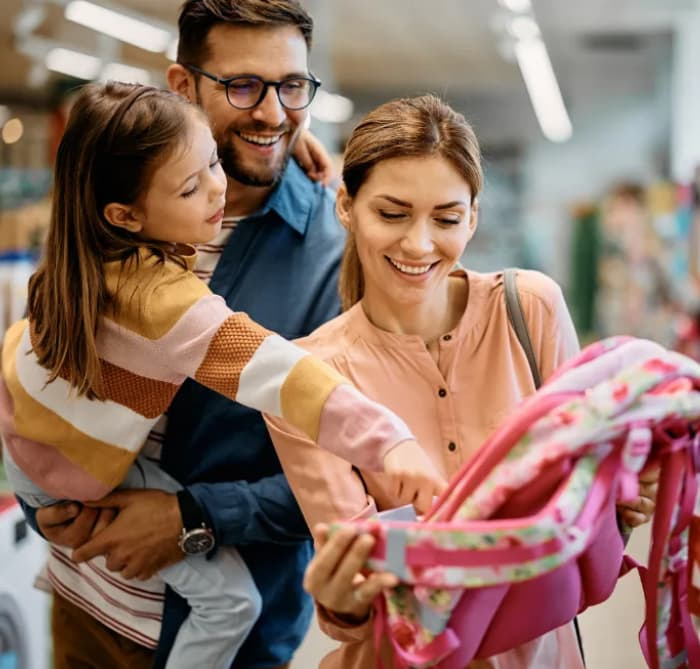 a mother and father buy a backpack for their daughter.