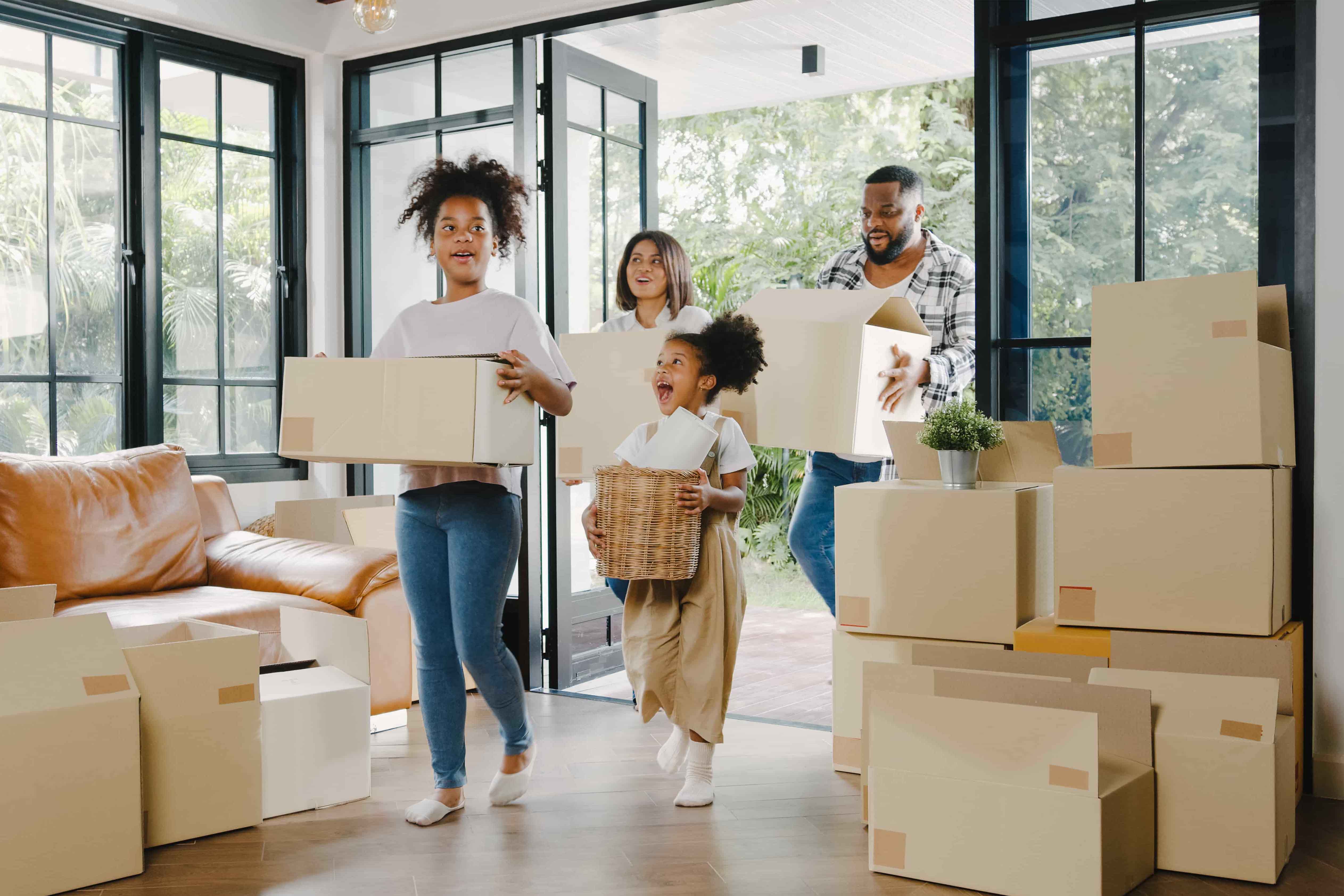 family carrying moving boxes into home